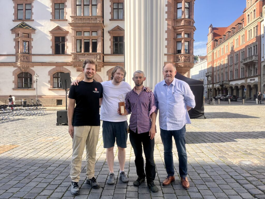 Jonathan Schörnig und Adrian J. Then (in der Mitte) mit dem Filmpreis „Leipziger Ring“, gemeinsam mit Nolte Bauer (links) und Prof. Dr. Rainer Vor von der Stiftung (rechts)